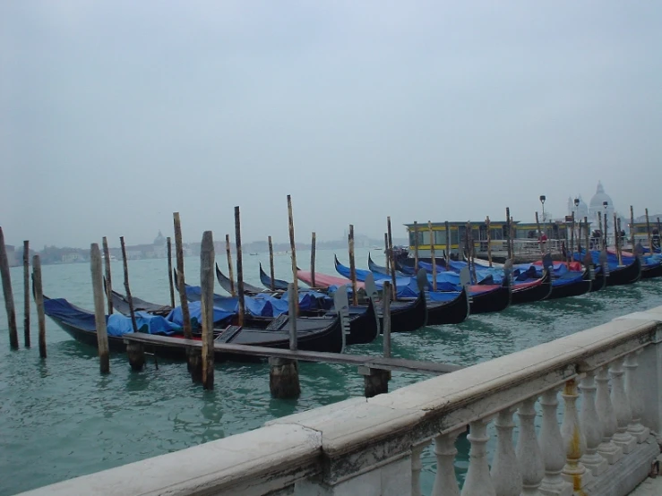 a row of boats parked in the water near a pier