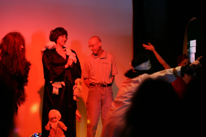 a group of people standing on a stage with one woman holding a teddy bear