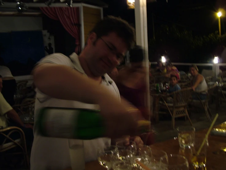 a man in white vest pouring a wine into a glass