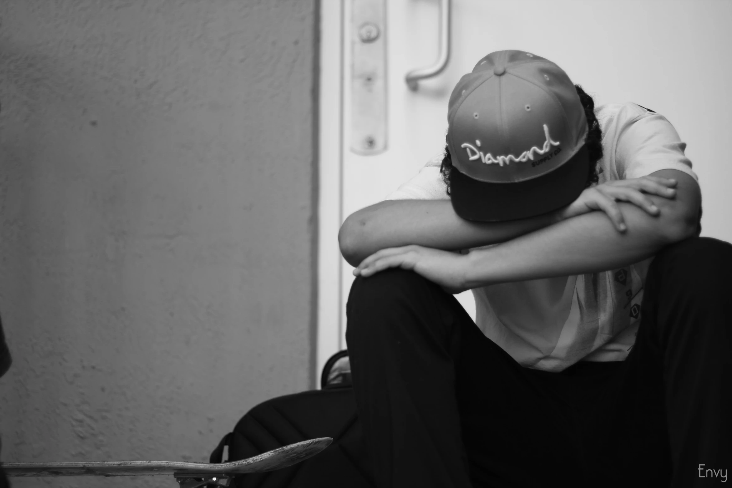 a woman in black pants and hat sitting on top of a skateboard