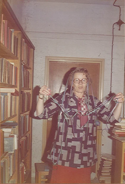 a woman in glasses holds up her hands