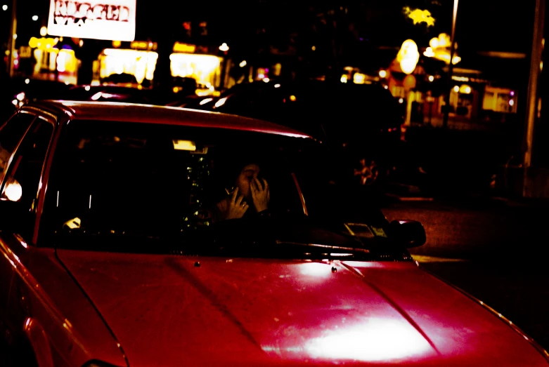 a red car parked on the side of a road at night