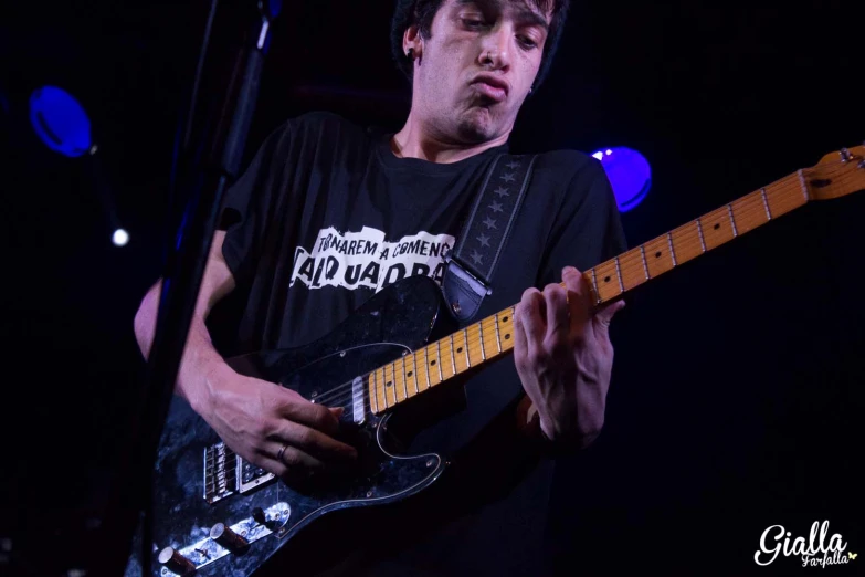 a man in black shirt playing guitar on stage
