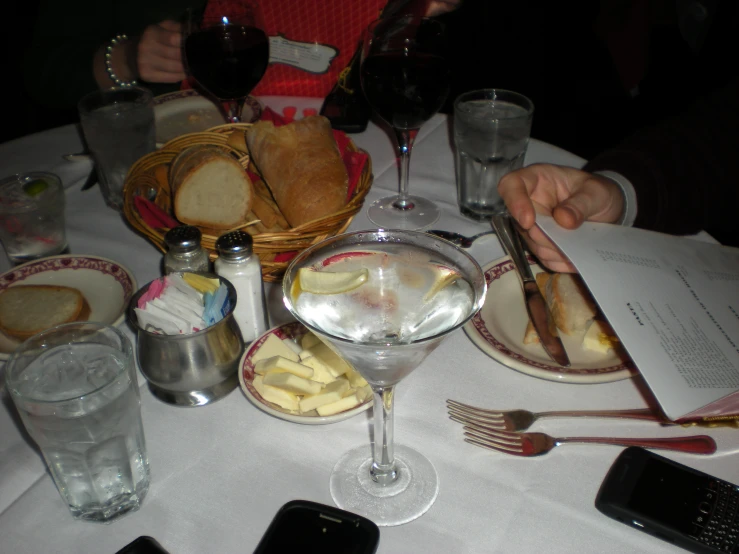 a table full of food, glasses and phone with wine