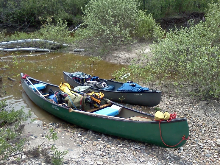 the green kayaks are sitting on the shore and ready to go into the water
