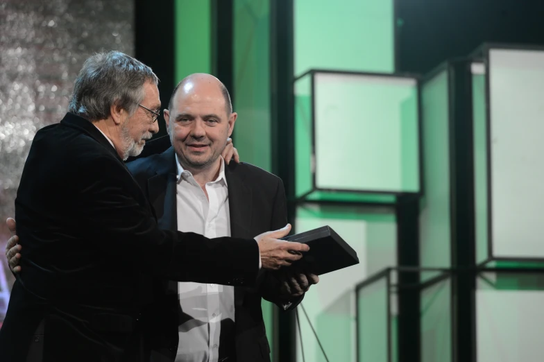 a close up of two men at a podium one holding a plaque