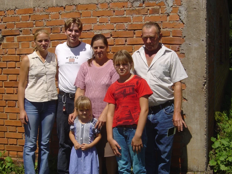 a family poses for a pograph in front of a brick wall