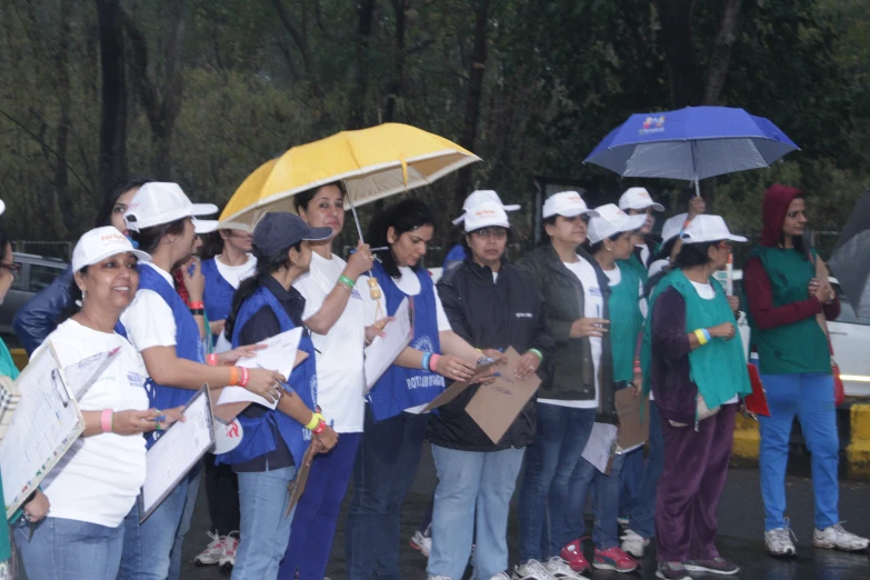 several women in construction hats stand together holding umbrellas