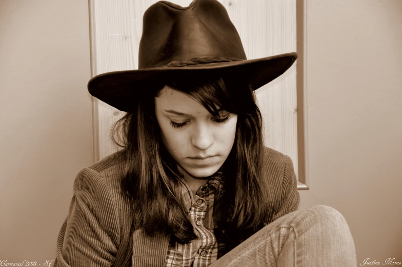 a lady sitting in a corner wearing a hat