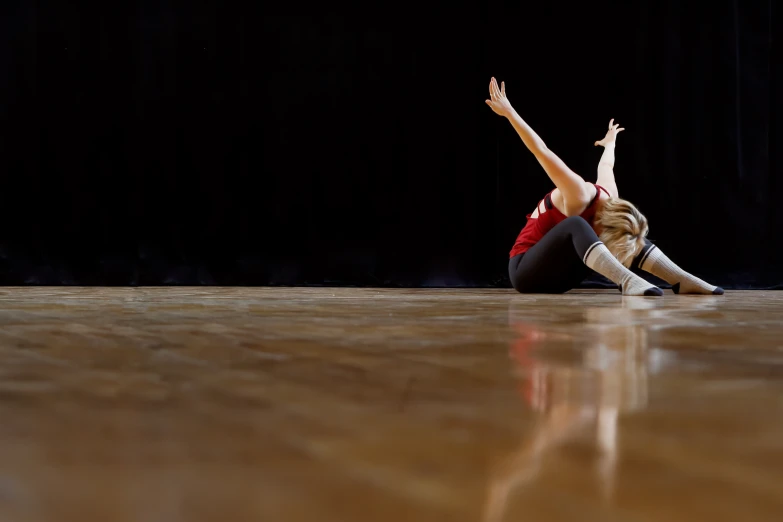 a girl is sitting on the floor doing a split handstand