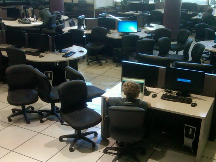 a room filled with desk and chairs covered in monitors