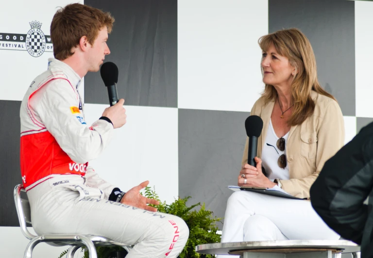 a woman talking to a man in a white suit and a microphone