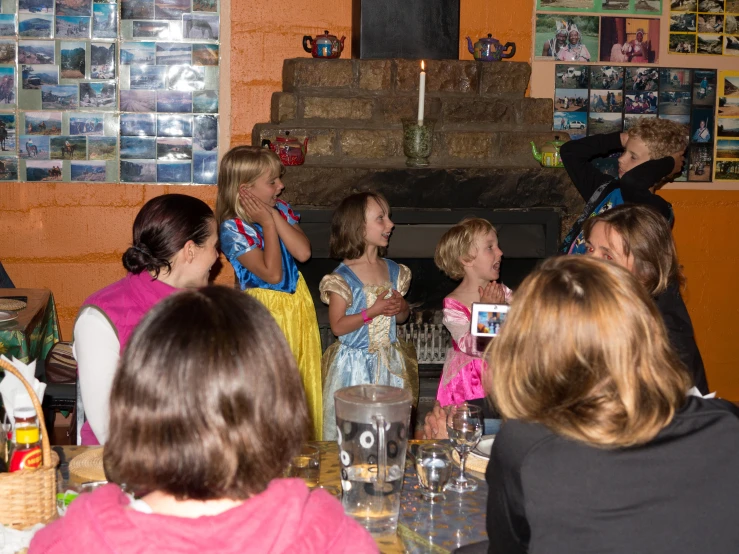 many girls sit at a table in front of the fireplace