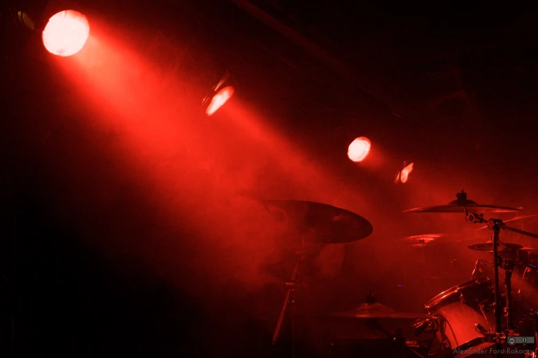 a po of drum sets on stage with bright red lights shining down