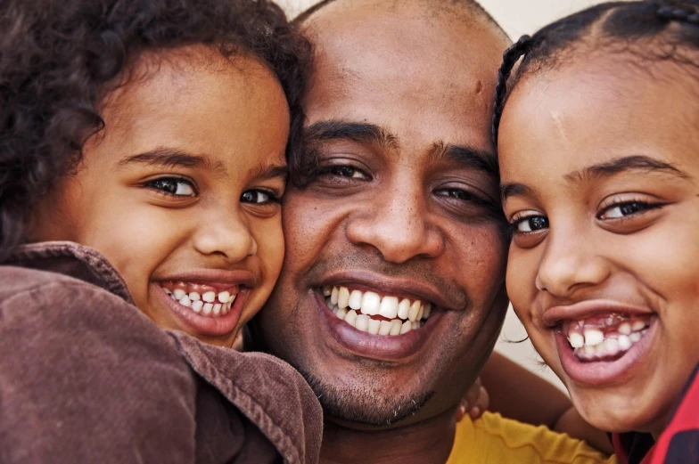 a man and two small children smiling together