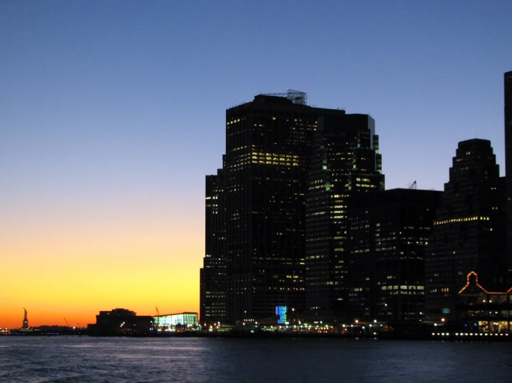 the skyline of tall skyscrs near water during sunset