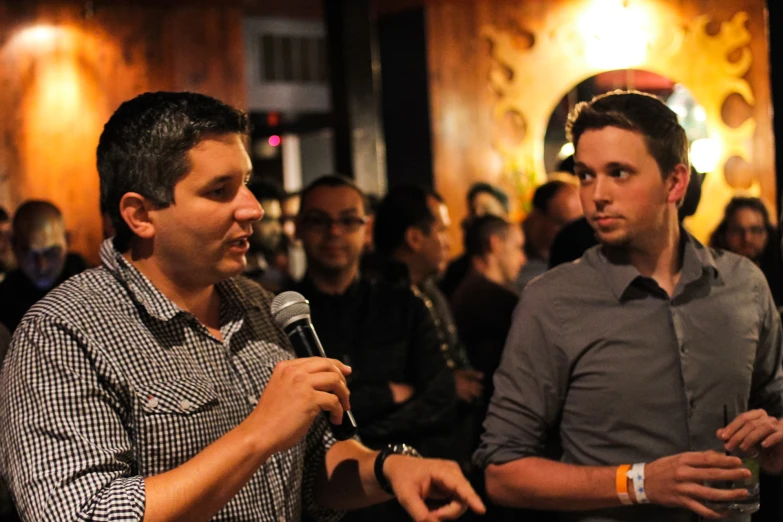 two men are talking to a crowd of people