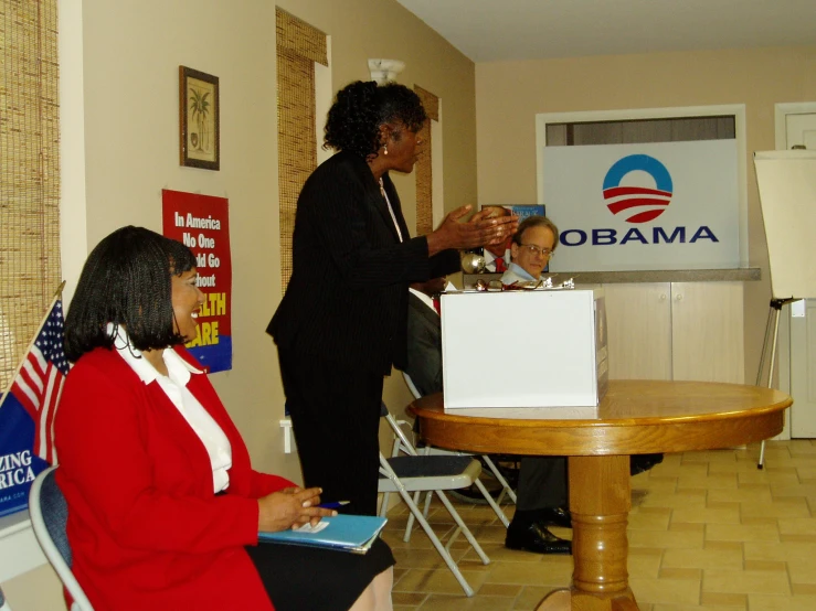 two women are sitting at a table and looking at the barack campaign sign