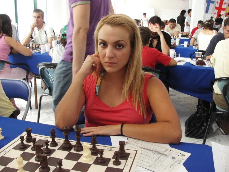 a young woman looking bored while playing chess