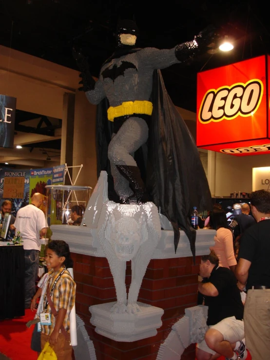 a statue of batman with his hand out on the top of a pedestal