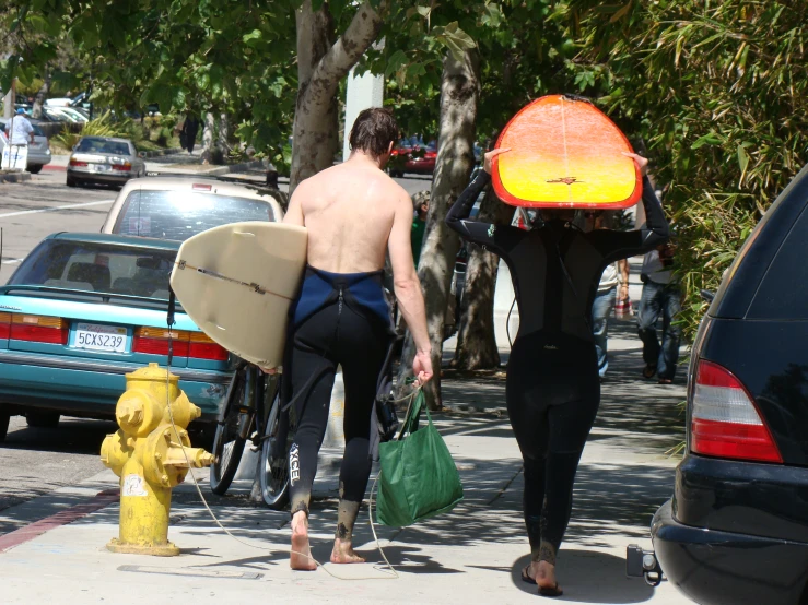 a man carrying a surfboard and a surfboard over his head while walking down the sidewalk