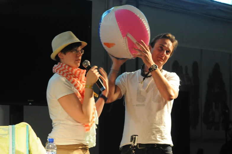 a man and a woman both holding up giant balls