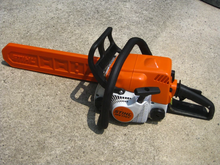 an orange chainsaw sitting on top of a cement ground