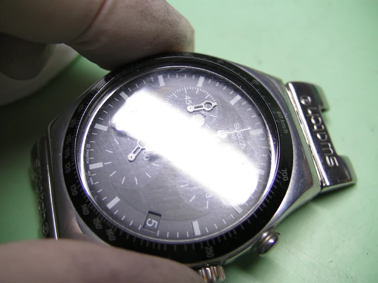 a man holding up a silver rolex watch on his wrist