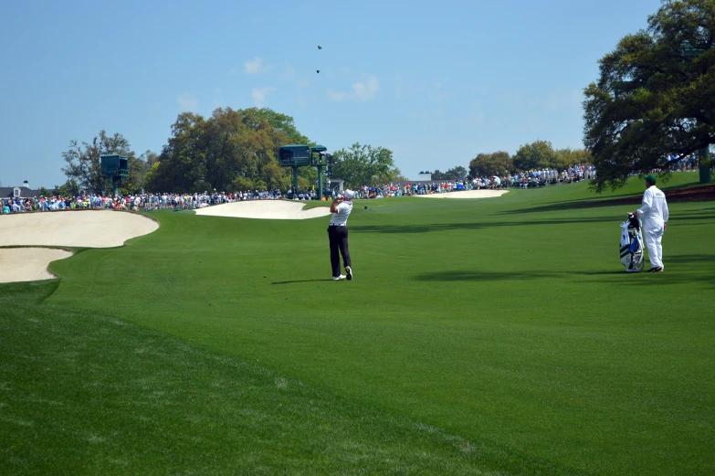 some people are walking across the field playing golf