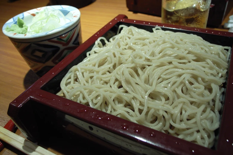 noodles and soup sitting in a red tray on a table