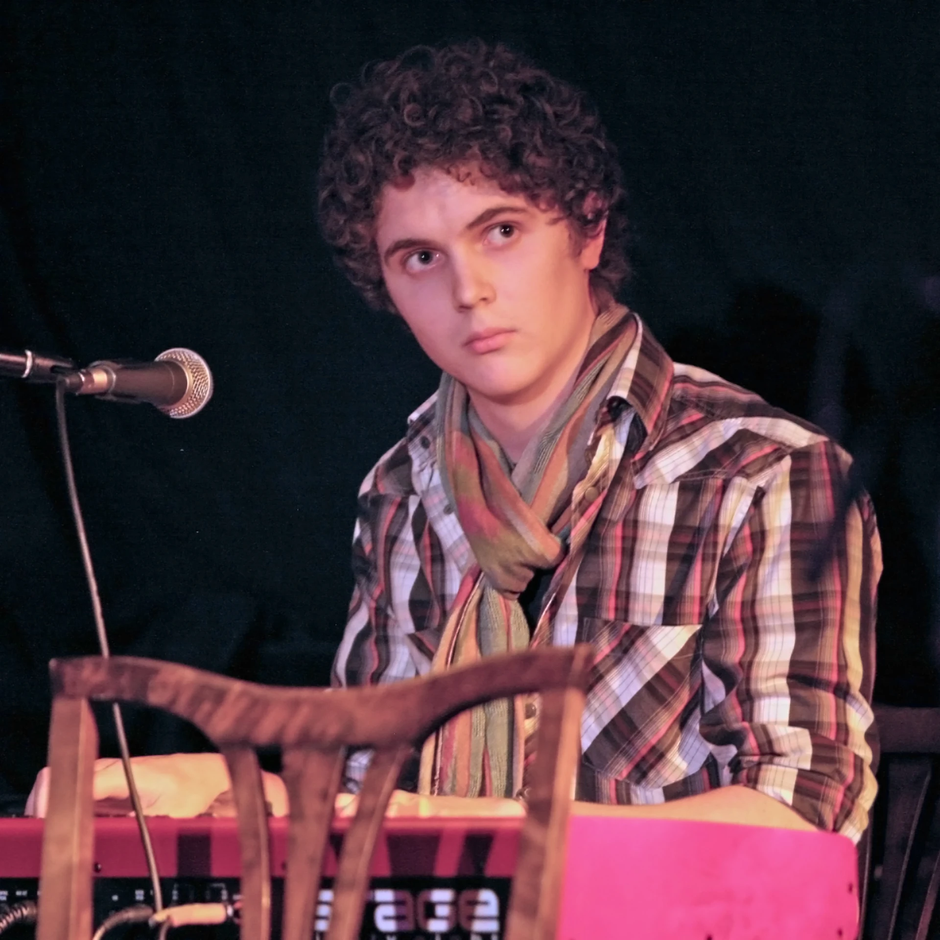 a young man is sitting at the piano in front of a microphone