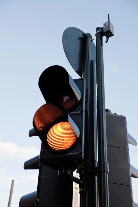 a stop light hanging on a pole by a street sign