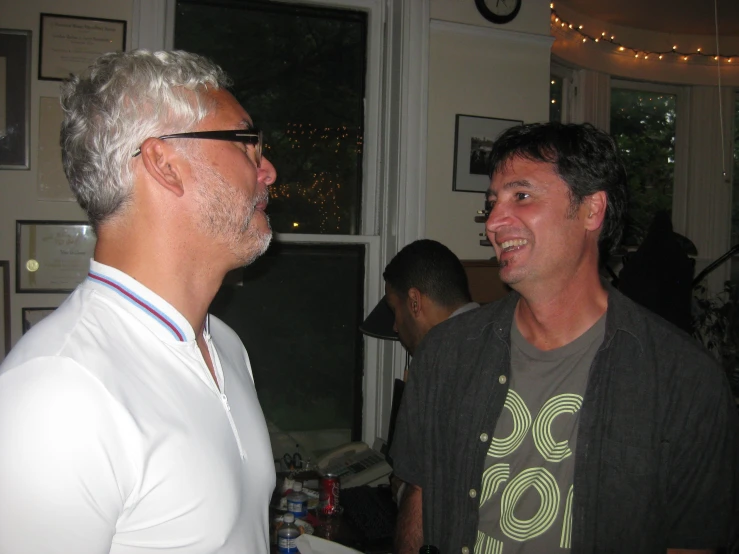 a man in glasses laughs with another man