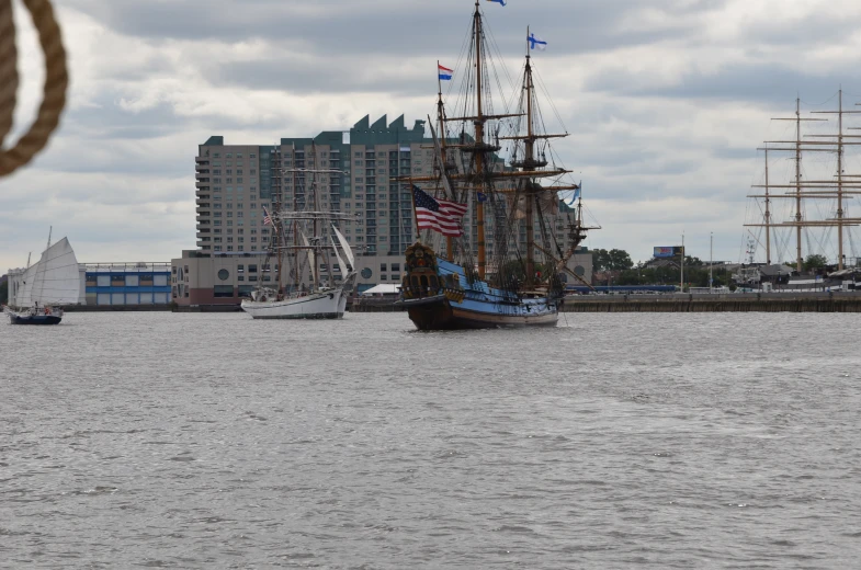 an old ship sailing next to the shore in front of the city