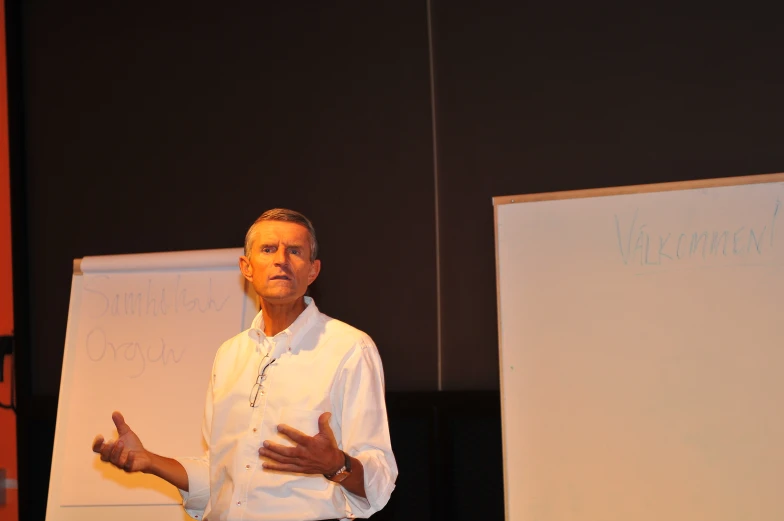 a man is speaking into microphone in front of a whiteboard