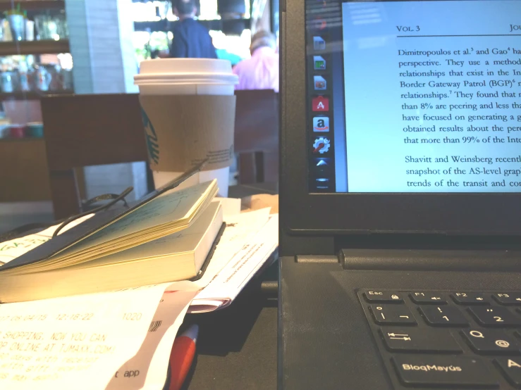 a laptop on a table with a book and a cup of coffee