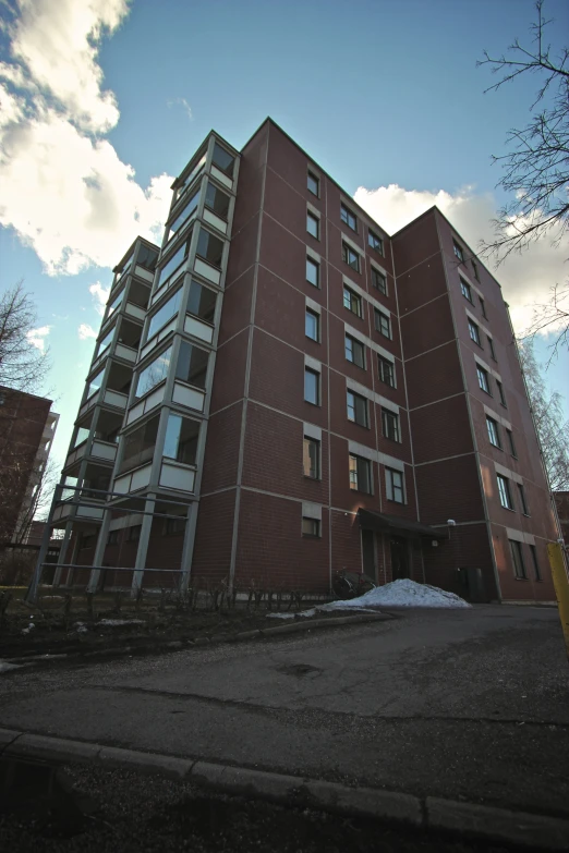 a very tall red building in front of a parking lot