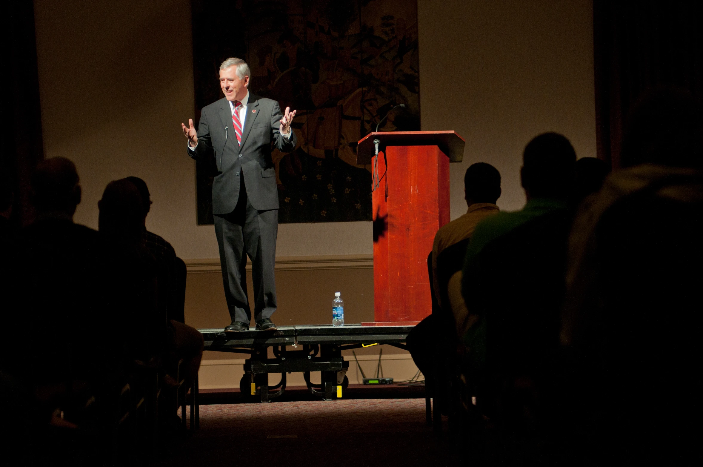 a man speaking at a podium in front of a group of people