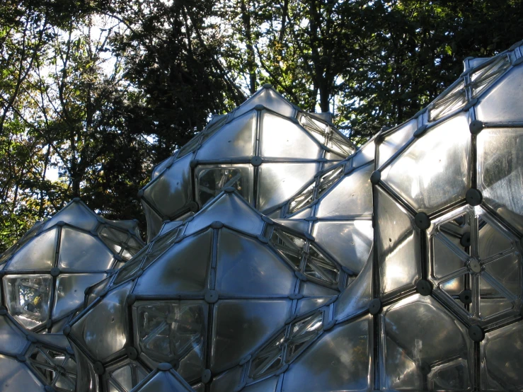 a group of stainless art pieces with trees in the background