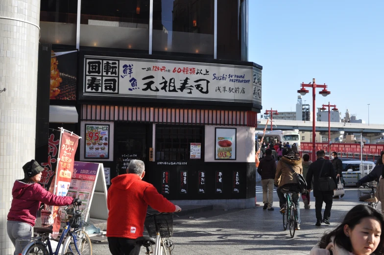 an asian business building with pedestrians walking by on the sidewalk