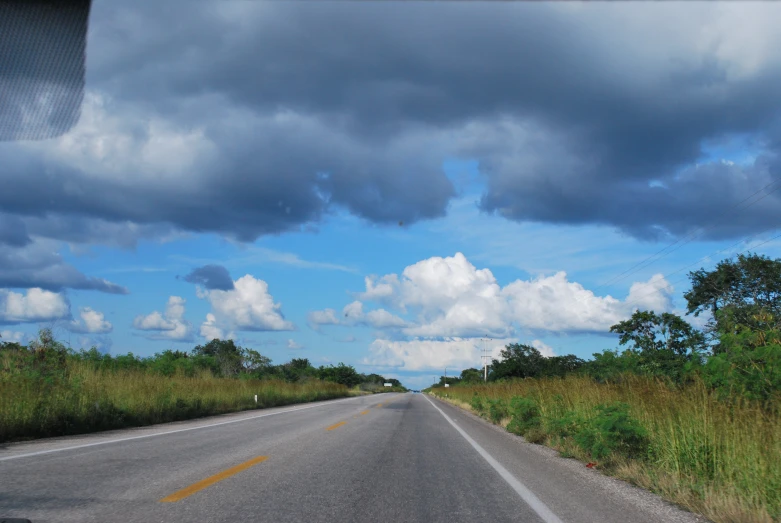 the cloudy sky is reflecting in the water along the road