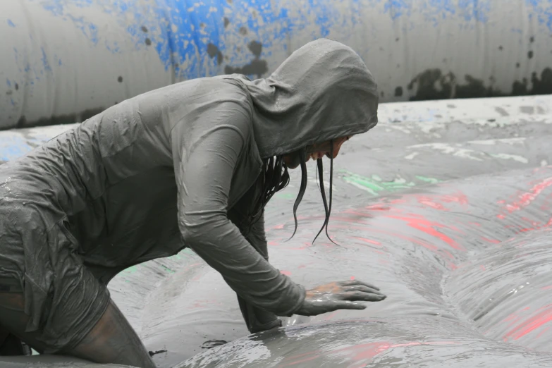 a person bending down in a swimming pool with wet clothing on