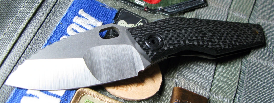 a sharp bladed knife resting on a black bladed pocket knife