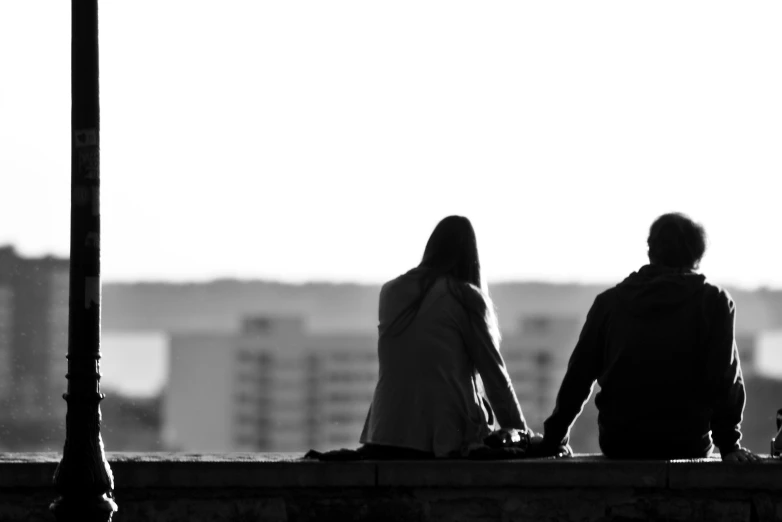 a man and woman are sitting on the wall