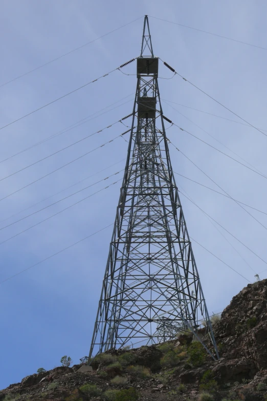 a view of a tall metal structure on a hill with lots of wires hanging over it