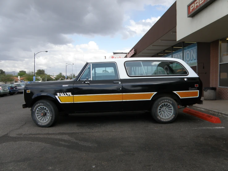 an old car parked in a parking lot with some other cars