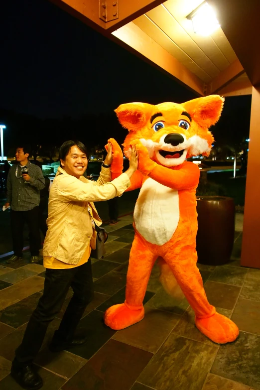 man petting an orange and white mascot on his hand