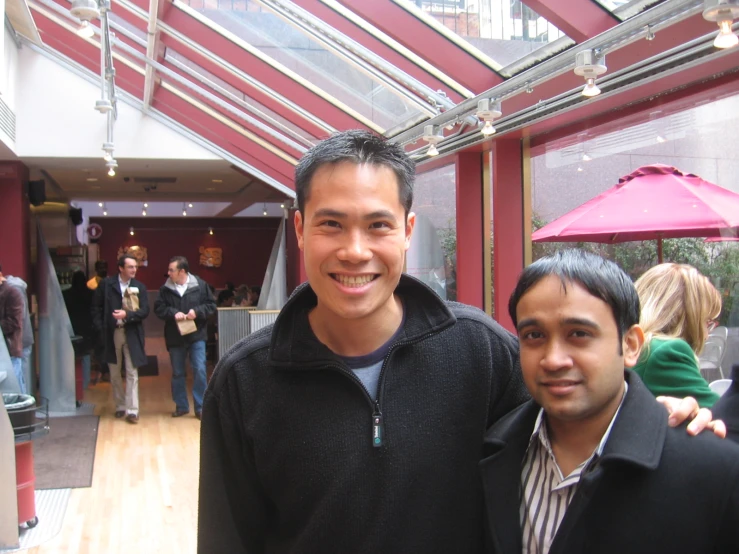 two men standing beside each other in front of a building