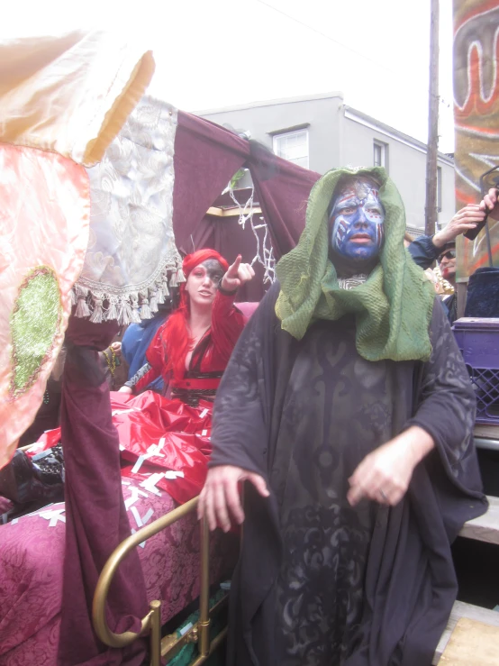 a man with an ornate face painted stands next to two people