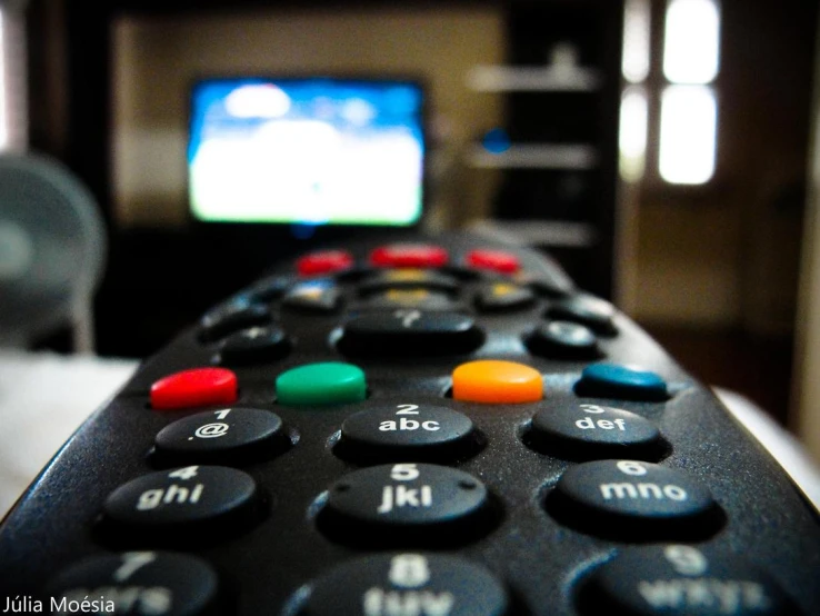 a close up view of an electric remote control and television screen